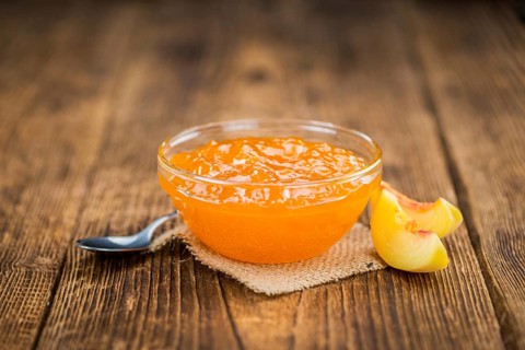 Homemade Peach Jam on an wooden table as detailed close-up shot, selective focus