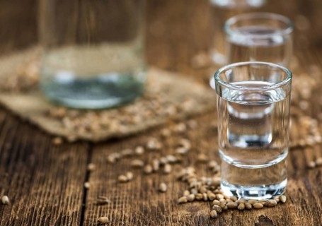 Wooden table with Wheat Liqueur (detailed close-up shot, selective focus)