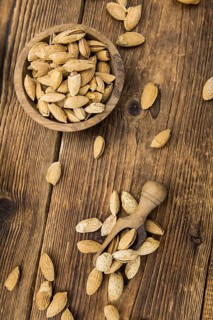 An old wooden table with roasted Almonds (in the shell) as detailed close-up shot (selective focus)