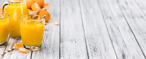 Homemade Tangerine Juice on an old and rustic wooden table (selective focus, close-up shot)