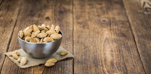 Roasted Almonds (in shell) on an old wooden table (close-up shot, selective focus)