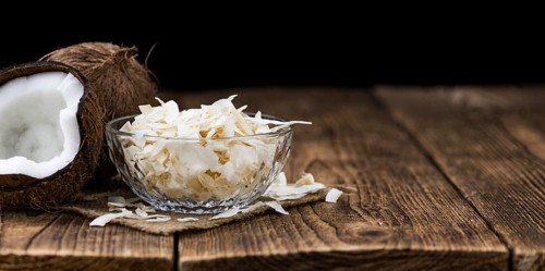 Healthy Coconut Flakes on a wooden table as detailed close-up shot (selective focus)
