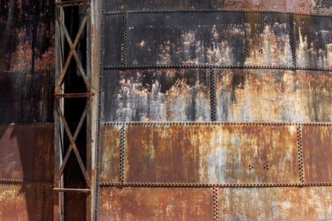 Riveted walls of an old gas storage tank, covered with rust, industrial monument Athens Gasworks