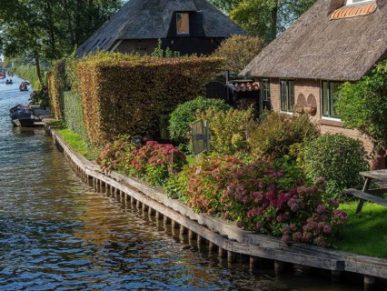Cosy house on the canal with well-kept hedge and blooming flowers along the bank, giethoorn,