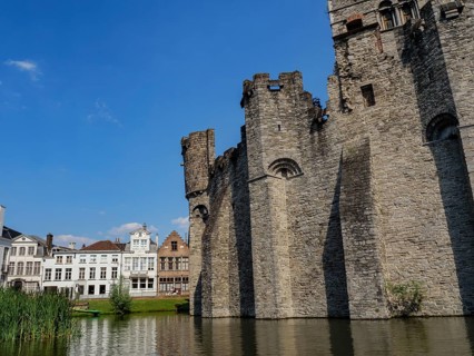 Massive medieval castle on the banks of a canal on a sunny day, Ghent, Belgium, Europe