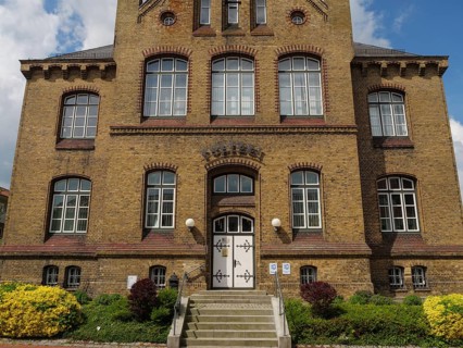 Historic brick building with numerous windows and stairs in a well-kept garden, Kappeln,
