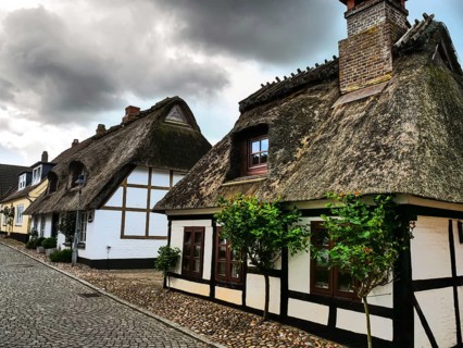 Idyllic village with traditional half-timbered houses and cobblestones under a cloudy sky,