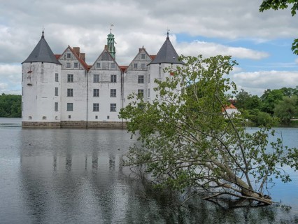 Mighty castle with white walls and striking towers, surrounded by a moat, Glücksburg,