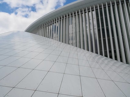 Close-up of a modern building with large windows, vertical struts and glassy structures reflecting