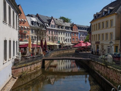 Cafés and historic buildings on a small canal, bridge and lively old town, Saarburg, germany