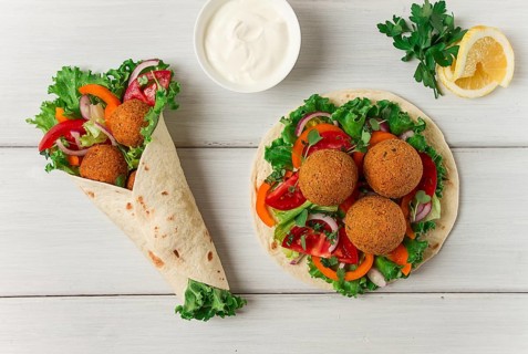 Tortillas, wrapped falafel balls, with fresh vegetables, vegetarian healthy food, on a wooden white
