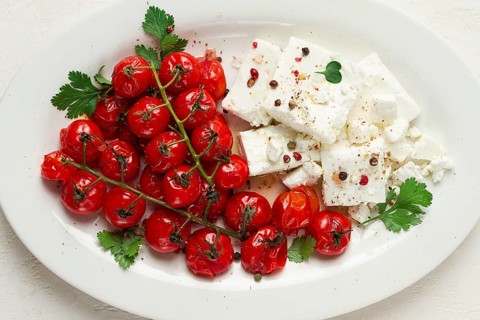 Gebackene Kirschtomaten, mit Käse und Gewürzen, auf einem weissen Teller, hausgemacht, keine Leute