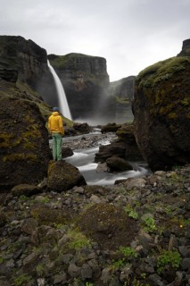 Young man with yellow jacket standing in front of waterfall, Haifoss and Granni waterfall at a