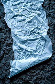 A piece of crumpled blue-toned paper on a dark background, emphasizing texture, AI generated