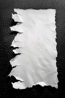 A piece of white torn paper with rough edges against a black textured background, AI generated
