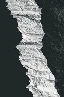 Crumpled paper creating a curved path with strong contrast between black and white, evoking texture