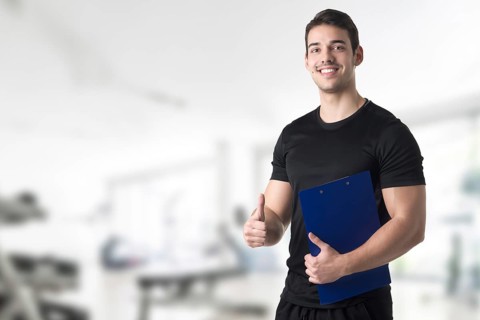 Personal trainer in a gym holding a notepad
