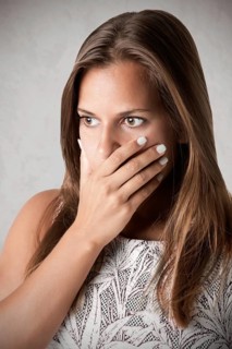 Closeup of a concerned woman covering her mouth, in a dark mood