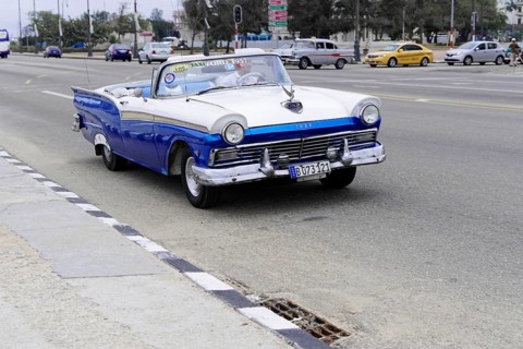 Havana, Cuba, Central America, A blue and white vintage car drives along a city street, Central