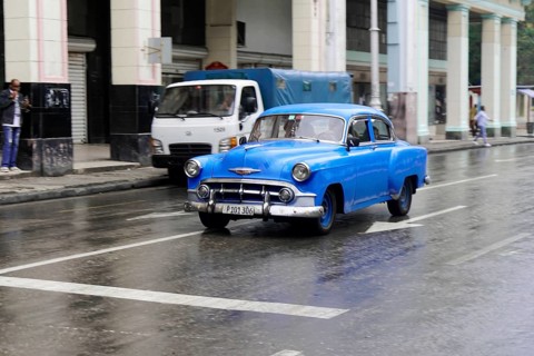 Havana, Cuba, Central America, Blue vintage car drives on wet road in the city, Central America