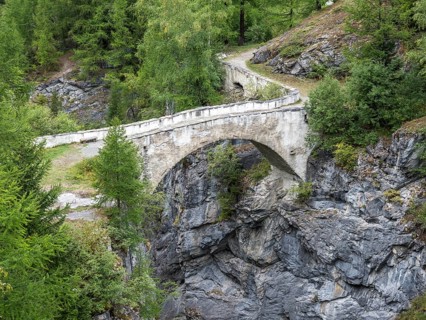 Historic bridge over narrow gorge just below water dam Barrage de Mauvoisin, Val de Bagnes,
