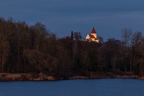 Illuminated church of Schaefstall near Donauworth above a lake in Bavaria