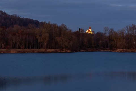 Illuminated church of Schaefstall near Donauworth above a lake in Bavaria