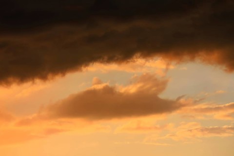Cloudy sky at sunset. The sky is visible through a gap in the clouds. The image conveys a mood of