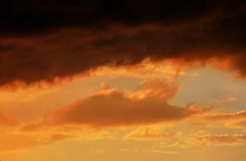 Cloudy sky at sunset. The sky is visible through a gap in the clouds. The image conveys a mood of