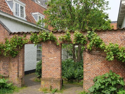 Idyllic garden with green brick arch and surrounding old buildings, Leiden, Netherlands