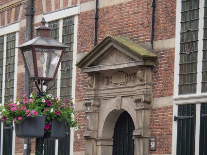 Historic façade with hanging flower baskets and an ornate lantern in the foreground, Leiden,
