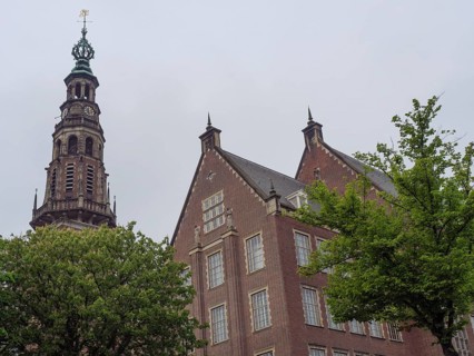 Historic building with imposing church tower and trees in the foreground under a grey sky, Leiden,