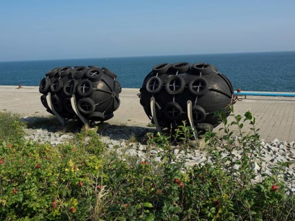 Black round fenders on the shore next to the blue sea under the clear sky, helgoland, germany