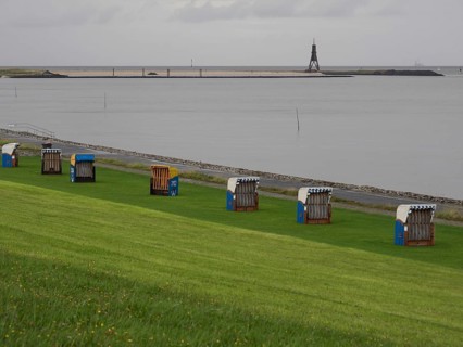 Beach chairs on a green meadow near the sea, with a beacon in the background, cuxhaven, germany
