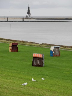 Several beach chairs on a green meadow near the sea under a cloudy sky, cuxhaven, germany