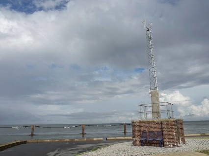 A radio mast on a brick base by the sea under a cloudy sky, cuxhaven, germany