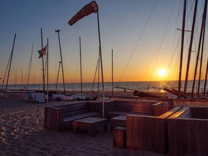Sailboats and empty seats on the beach at sunset with calm sea and sandy bottom, De Haan, Flanders,
