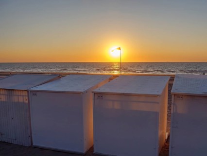 Sunset over the sea, beach with white huts, quiet and peaceful atmosphere with a warm light, De
