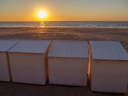 Sunset on the beach with white huts, empty sandy area and calm atmosphere, sea in the background,