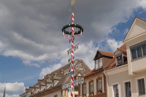 Festive street view with a decorated wagon wheel and flags, houses in the background, speyer,