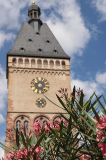 Gothic clock tower with floral decorations in the foreground, blue sky with clouds, speyer, germany