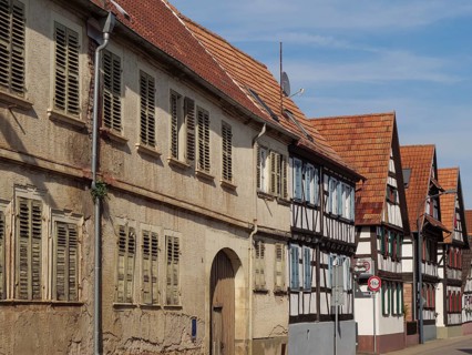 Row of old half-timbered houses with red roofs and shutters along a sunny street, Kandel,