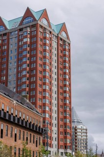 Tall modern residential building with red and grey facades and glass elements, rotterdam, the