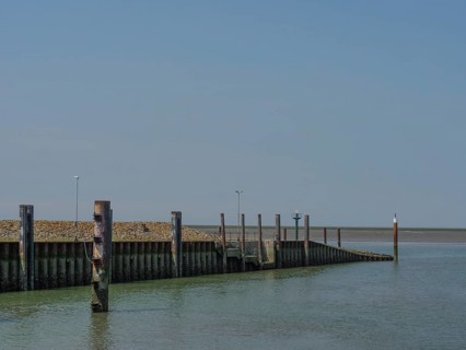 Quiet harbour with wooden piles and a clear sky over the sea, hallig hooge, schleswig-holstein,
