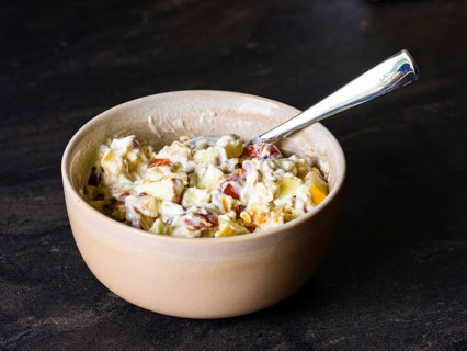 Fresh homemade muesli with organic fruit and rolled oats mixed in natural yoghurt in a ceramic bowl