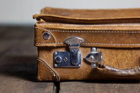 An old suitcase on the floorboard, old shabby leather portable suitcase for travel trip on floor