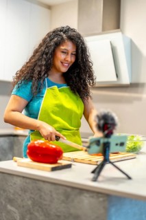 Vertical photo of a latin young female pretty live streamer cooking healthy food online
