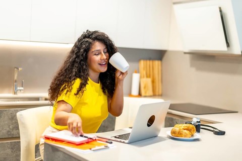 Female latin young content creator working at home while drinking coffee at morning sitting in the