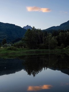 Evening clouds reflected in the lake, mountain peak of Admonter Reichenstein in the background,