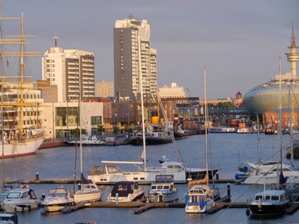 Harbour view with several yachts and boats in front of a city backdrop of skyscrapers in the